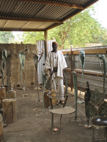 BURKIINA FASO 25 (UAGADUGU-EL GRAN MERCADO) ESCULTOR EN BRONCE, CON UNA OBRA MUY CREATIVA