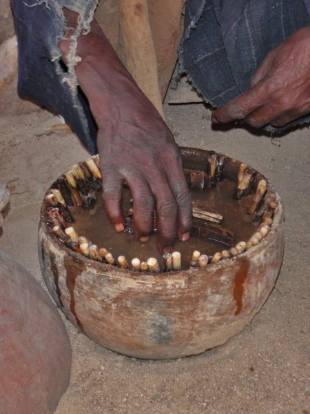 CAMERUN 50 EL BRUJO DE LOS CANGREJOS. EMPIEZA EL CEREMONIAL, EN UN CUENCO VA CLAVANDO BASTONCITOS, QUE REPRESENTAN, EL UNIVERSO, LA TIERRA, AFRICA, CAMERUN, RUMSHIKI, ... LOS HOMBRES, LOS ANTEPASADOS, LOS ESPIRITUS, NOSOTROS, NUESTRA FAMILIA... ETC